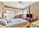 A bedroom features a ceiling fan, closet, large bed, and an old-style dresser with a lamp at 7601 226 E St, Bradenton, FL 34211