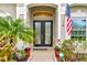 Close-up of front door with decorative glass, potted plants, American flag, and Ring doorbell for added security at 7601 226 E St, Bradenton, FL 34211