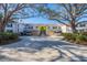 View of the building entrance with manicured landscaping, covered parking, and palm trees at 801 Montrose Dr # 202, Venice, FL 34293