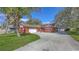 Exterior shot of a charming red stucco home with a wide driveway and mature palm trees, with an additional detached garage at 829 Gantt Ave, Sarasota, FL 34232