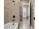 Bright bathroom with a tub, shower, tile surround, and an open doorway leading into another room at 10406 Eastwood Dr, Bradenton, FL 34211