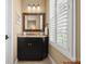 Bathroom with a black vanity, granite countertop, a large mirror, and plantation shutters at 10406 Eastwood Dr, Bradenton, FL 34211