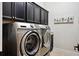 Laundry room with stainless steel front loading washer and dryer, with dark cabinets above and a tile floor at 10406 Eastwood Dr, Bradenton, FL 34211