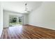 Bright living room with wood floors, a ceiling fan, and sliding glass doors leading to the backyard at 1122 Knotty Pine Ave, North Port, FL 34288