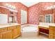 Bright main bathroom with a soaking tub, red textured wallpaper, and glass block window for privacy at 12211 Lavender Loop, Bradenton, FL 34212