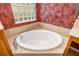 Bright bathroom featuring a soaking tub, glass block window, red textured wallpaper at 12211 Lavender Loop, Bradenton, FL 34212