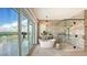 Modern bathroom featuring a soaking tub, glass shower, and serene views of the water at 1300 Tangier Way, Sarasota, FL 34239