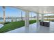 Covered patio with stone floors overlooking a lush green lawn and waterfront at 1300 Tangier Way, Sarasota, FL 34239