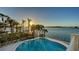Beautiful backyard pool area with lush tropical landscaping and stunning water views at sunset at 1300 Tangier Way, Sarasota, FL 34239