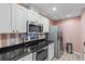 Modern kitchen with white cabinets, stainless steel appliances, and black countertops at 16211 Rambling Vine W Dr, Tampa, FL 33624