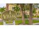 Community signage with pineapple emblem at Villas on Laurel, with landscaping and a partial view of the building in the background at 1685 Laurel St # 4, Sarasota, FL 34236