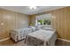 Comfortable bedroom with twin beds, ceiling fan, and wood paneled walls and a bright window at 1874 Woodstock Ln, Sarasota, FL 34234