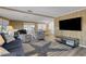 Living room with wood-look walls, large TV, and comfortable seating, plus a dining area beyond at 1874 Woodstock Ln, Sarasota, FL 34234