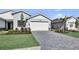 Charming single-Gathering home featuring a brick driveway, a two-car garage, and beautifully landscaped front yard at 18803 Dayspring Pl, Venice, FL 34293