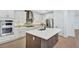 Modern kitchen featuring white cabinets, stainless steel appliances, a central island, and backsplash at 18803 Dayspring Pl, Venice, FL 34293