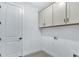 Bright laundry room features upper cabinets and a door, perfect for organizing household tasks at 18803 Dayspring Pl, Venice, FL 34293