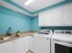 A dedicated laundry room with a utility sink, white cabinets, and sleek appliances at 2410 Harbourside Dr # 121, Longboat Key, FL 34228