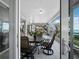 An enclosed sunroom patio is set up for dining with comfortable furniture and serene water views at 2410 Harbourside Dr # 121, Longboat Key, FL 34228