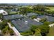 An aerial view of multiple well-maintained tennis courts surrounded by lush greenery and waterways at 2410 Harbourside Dr # 121, Longboat Key, FL 34228