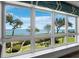 A stunning water view is seen through a large window overlooking a manicured lawn and bright, sunny skies at 2410 Harbourside Dr # 121, Longboat Key, FL 34228