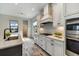 Modern kitchen featuring white cabinets, stainless steel appliances, and a stylish range hood at 26833 Weiskopf Dr, Englewood, FL 34223