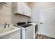 Laundry room features wood-look tile, white cabinets with shelving, and modern washer and dryer units at 26833 Weiskopf Dr, Englewood, FL 34223