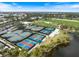 Aerial shot highlighting several well-maintained tennis and pickleball courts adjacent to a pond at 26833 Weiskopf Dr, Englewood, FL 34223