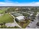 Aerial view of multiple tennis courts and clubhouse amidst lush landscaping and nearby parking at 26833 Weiskopf Dr, Englewood, FL 34223