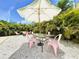Outdoor dining area with a glass table, pink chairs, and a shaded umbrella at 3228 Webber St, Sarasota, FL 34239
