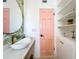 Stylish bathroom featuring a decorative vanity, round mirror, and pink accent door at 3228 Webber St, Sarasota, FL 34239