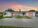 Charming single-story home with a white exterior, complemented by a colorful pink door and garage at 3228 Webber St, Sarasota, FL 34239