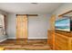 Bedroom with hardwood floors, a sliding barn door, and a dresser with a tv at 34200 State Road 62, Parrish, FL 34219