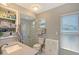 Bright bathroom featuring a glass-enclosed shower, white cabinets, and a sink with shelving at 3702 Torrey Pines Way, Sarasota, FL 34238