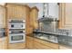 Close up of kitchen appliances, including double oven, gas stove, and custom vent hood at 3751 Eagle Hammock Dr, Sarasota, FL 34240