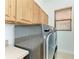 Functional laundry room with wood cabinets and a modern gray front load washer and dryer at 3751 Eagle Hammock Dr, Sarasota, FL 34240