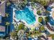 Aerial view of a kidney-shaped community pool, surrounded by lounge chairs, tables with umbrellas, and lush landscaping at 383 Aruba Cir # 102, Bradenton, FL 34209