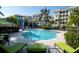 Resort style pool with lounge chairs and tables with umbrellas and lush landscaping in view of condo buildings at 383 Aruba Cir # 102, Bradenton, FL 34209