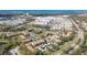 Aerial shot of condos nestled among green trees, a shopping center, and a pond under a blue sky at 4008 Crockers Lake Blvd # 13, Sarasota, FL 34238