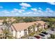 Tan two-story condo building showing landscaping and parking area on a sunny, tropical day at 4008 Crockers Lake Blvd # 13, Sarasota, FL 34238