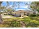 Exterior view features a tan home with a brick driveway, mature landscaping, gated courtyard, and a dark vehicle at 4452 Oakley Greene # 49, Sarasota, FL 34235