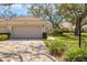 Exterior view features a tan home with a brick driveway, mature landscaping, and partial view of another residence at 4452 Oakley Greene # 49, Sarasota, FL 34235