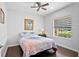 Cozy bedroom with wood floors, a ceiling fan, and a bright window overlooking the property at 4574 Cedar Brush Ter, Sarasota, FL 34243