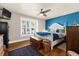 Cozy bedroom with hardwood floors, a blue accent wall, plantation shutters, and stylish furniture at 503 Park Dr, Bradenton, FL 34209