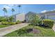 Garage and driveway with beautiful landscaping, including lush greenery and flowers, with palm trees in the background at 513 Woodstork Cir, Bradenton, FL 34209