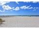 Wide sandy beach with people enjoying the sun and sea, under a bright blue sky filled with fluffy clouds at 515 Rousseau Dr, Nokomis, FL 34275