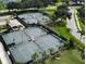 Aerial view features four well-maintained tennis courts, with palm trees and lush greenery at 5320 Hyland Hills Ave # 2222, Sarasota, FL 34241