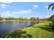 Serene backyard featuring a tranquil lake, lush green grass, and mature trees at 5539 Octonia Pl, Sarasota, FL 34238
