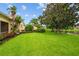 Professionally landscaped backyard with mature trees, shrubs and manicured lawn leading to the lake at 5539 Octonia Pl, Sarasota, FL 34238