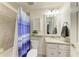 Well-lit bathroom featuring granite counters, tile flooring, and a shower with a stylish blue shower curtain at 5710 Palmer Cir # 204, Lakewood Ranch, FL 34211