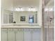 Bathroom featuring double sinks with granite counters, white cabinets, and a glass-enclosed walk-in shower at 5710 Palmer Cir # 204, Lakewood Ranch, FL 34211